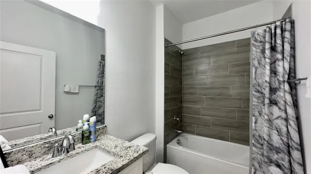 a bathroom with a granite countertop shower sink vanity and a bathtub