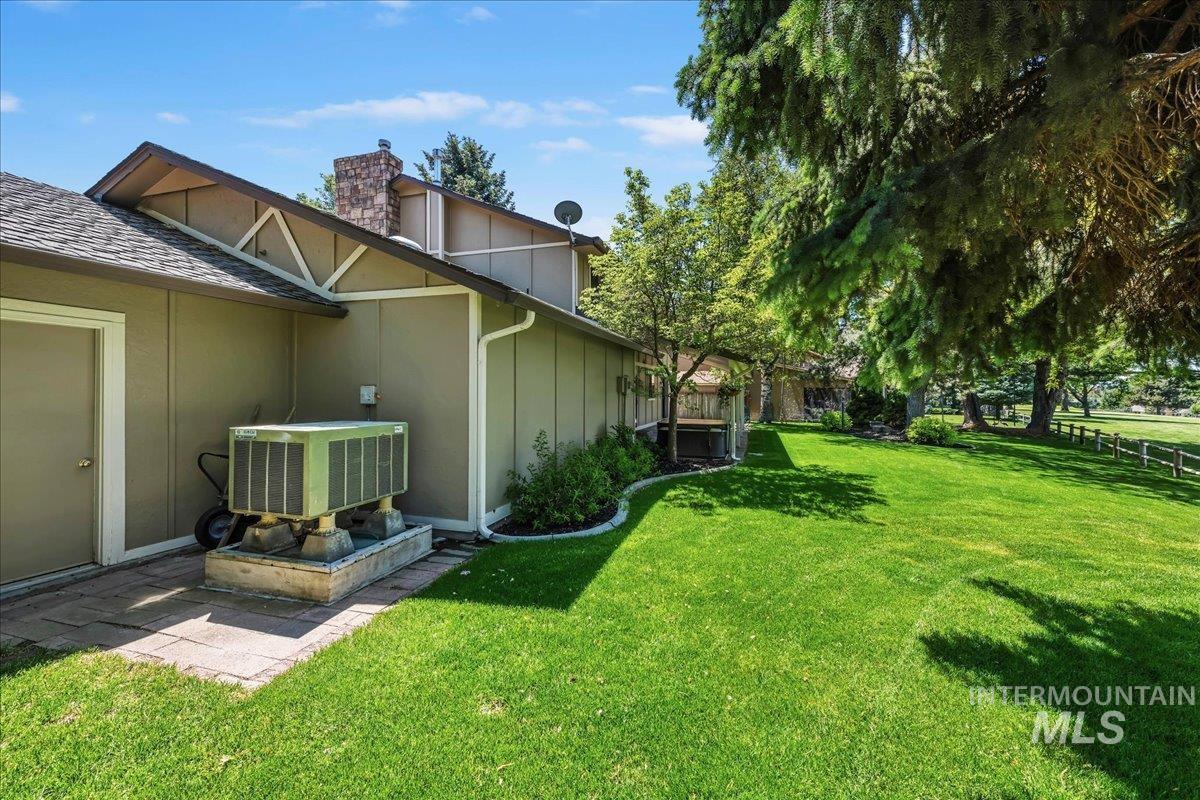 599 Pebble Beach Way Eagle, ID 83616 - Photo 36 of 44 Expansive green lawn bordering the property, featuring mature trees and a wood fence