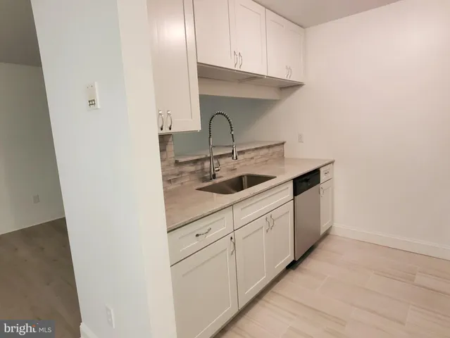a kitchen with white cabinets and sink