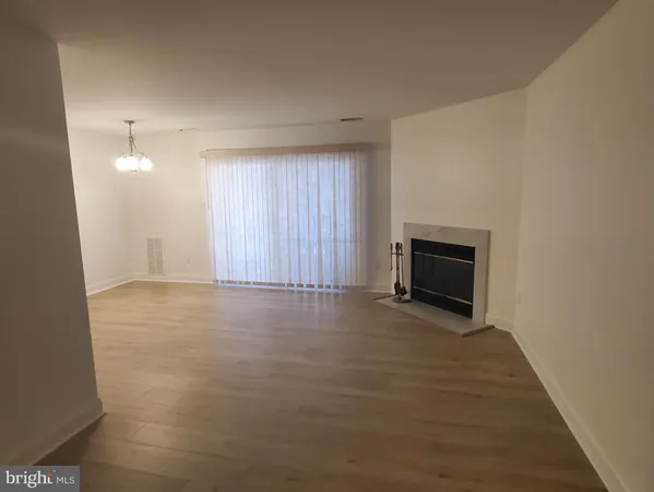 a view of empty room with wooden floor and fireplace