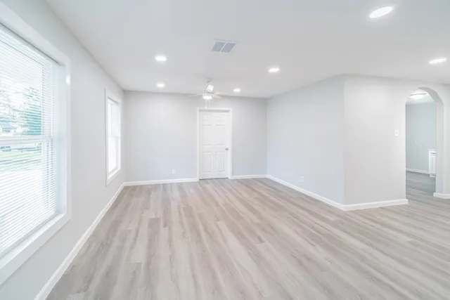 a view of an empty room with wooden floor and a window