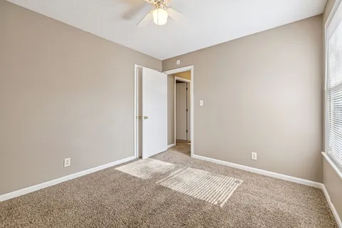 an empty room with windows and chandelier fan