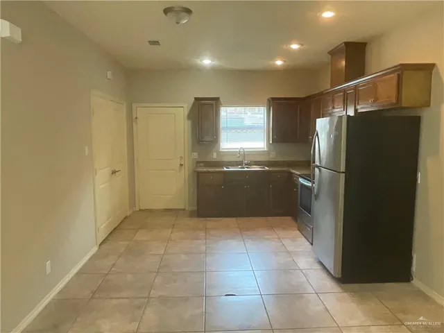 a view of a electric refrigerator in kitchen and an empty room