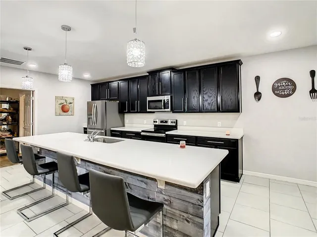 a kitchen with stainless steel appliances granite countertop a sink dishwasher a stove a refrigerator and a dining table with wooden cabinet