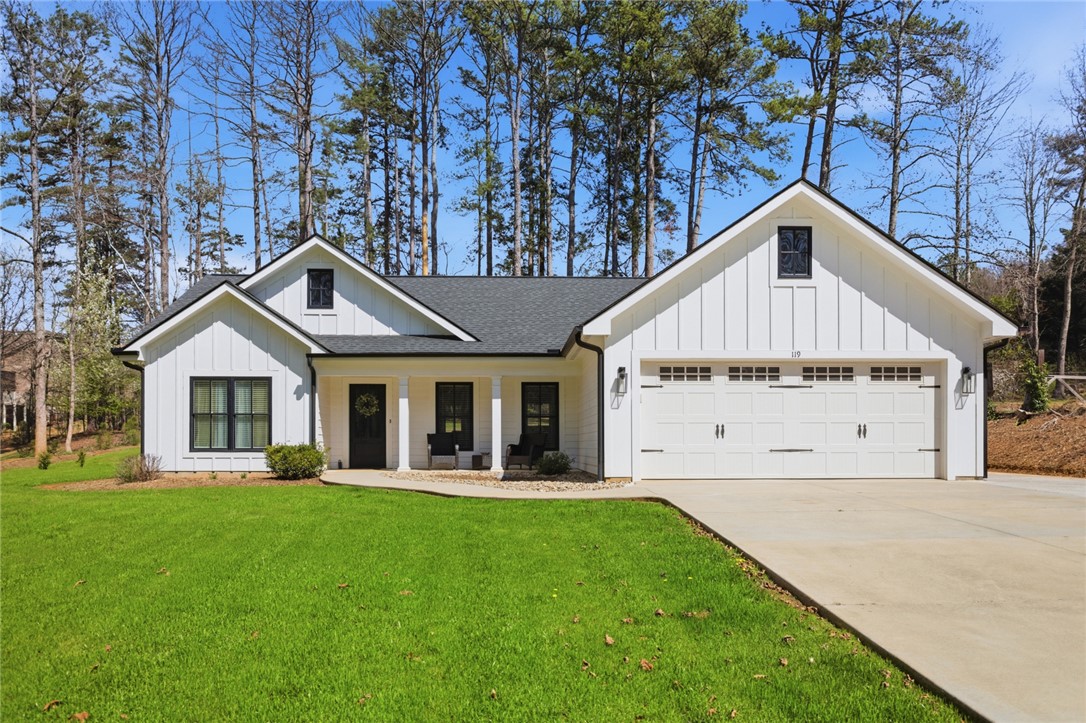 This charming modern farmhouse features a pristine white exterior, a spacious garage, and an inviting front porch.