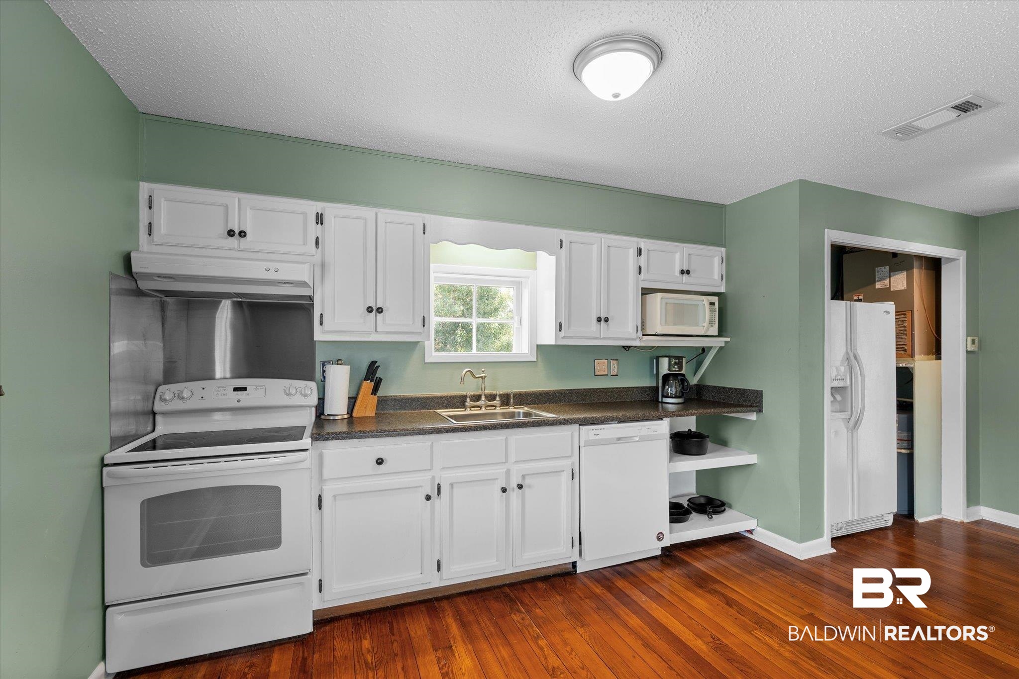 1953 Dauphin Street Mobile, AL 36606 - Photo 39 of 56 Kitchen featuring white cabinets, exhaust hood, and white appliances