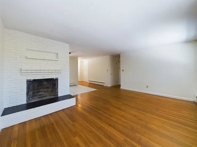a view of empty room with wooden floor and fireplace
