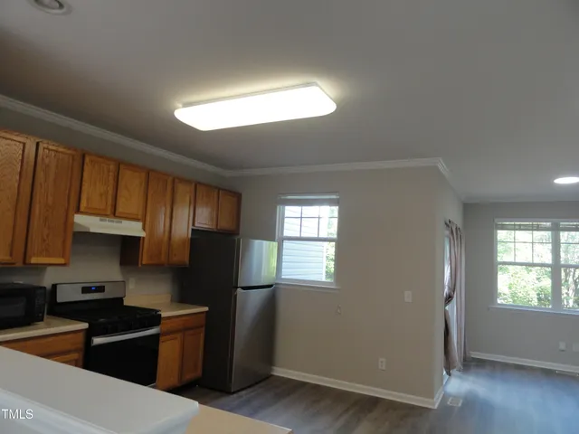 a kitchen with stainless steel appliances granite countertop a refrigerator a sink dishwasher a stove and white countertops with wooden floor