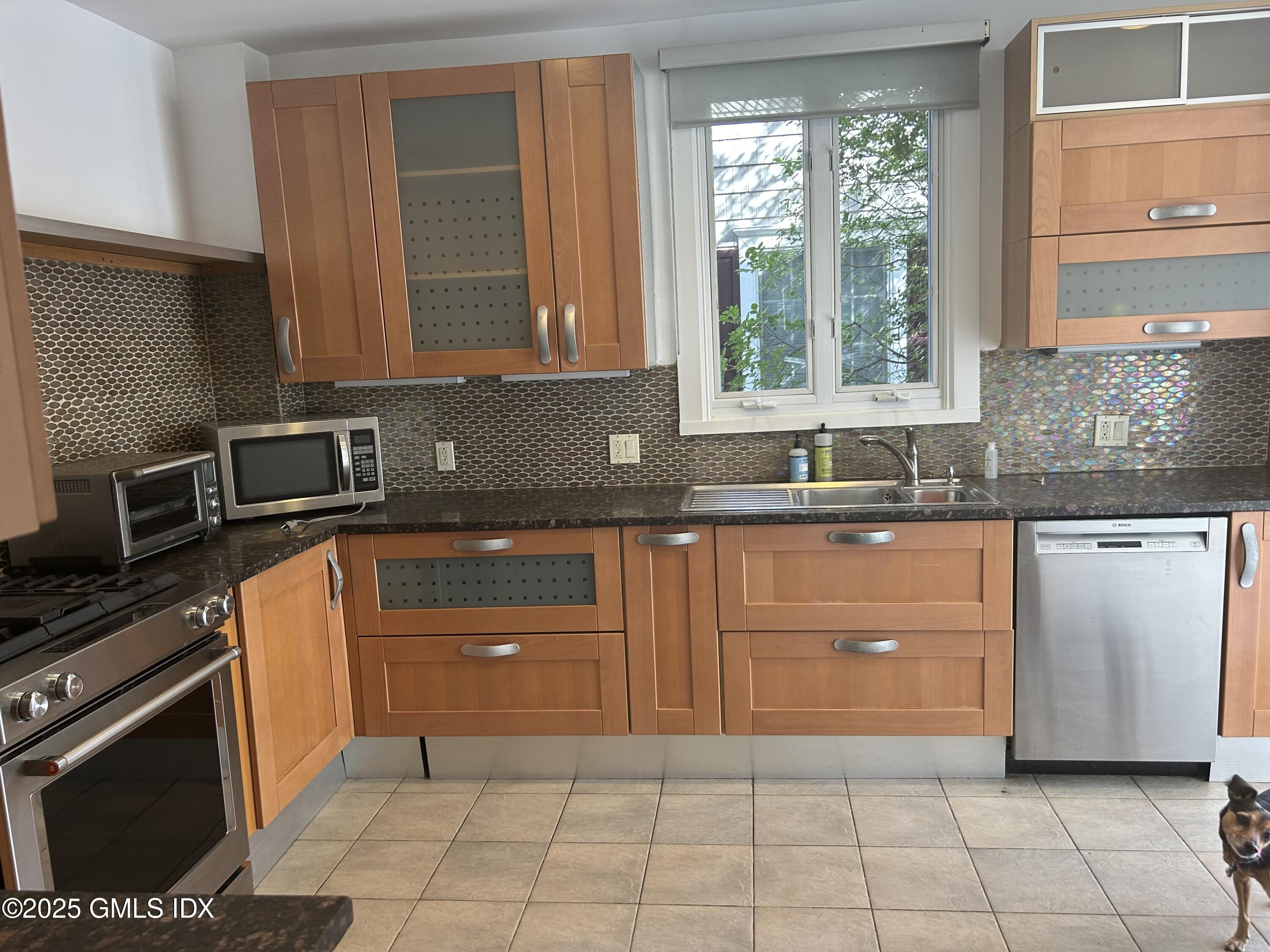 112 East Elm Street, Unit 1 Greenwich, CT 06830 - Photo 2 of 19 a kitchen with granite countertop a sink a stove and cabinets