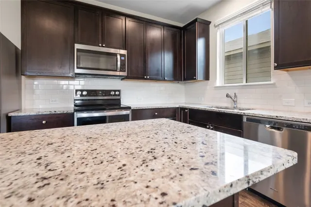 a kitchen with stainless steel appliances kitchen island granite countertop a sink stove and microwave