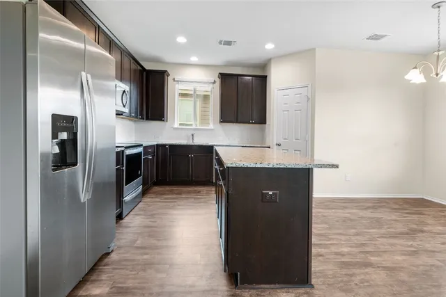 a large kitchen with stainless steel appliances granite countertop a refrigerator and a sink