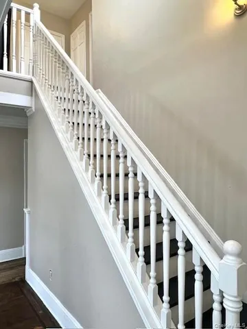 a view of staircase with railing and white walls