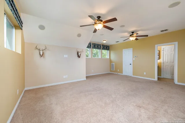 an empty room with ceiling fan and windows