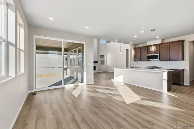 a large kitchen with stainless steel appliances kitchen island a large counter top and wooden floors
