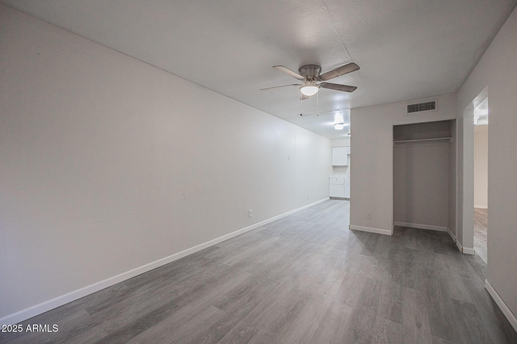 2340 East Broadway Road, Unit A Mesa, AZ 85204 - Photo 2 of 14 an empty room with wooden floor and ceiling fan