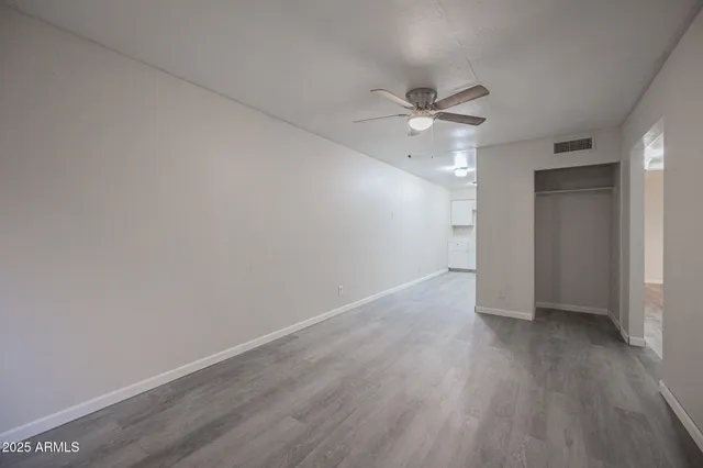 an empty room with wooden floor and ceiling fan