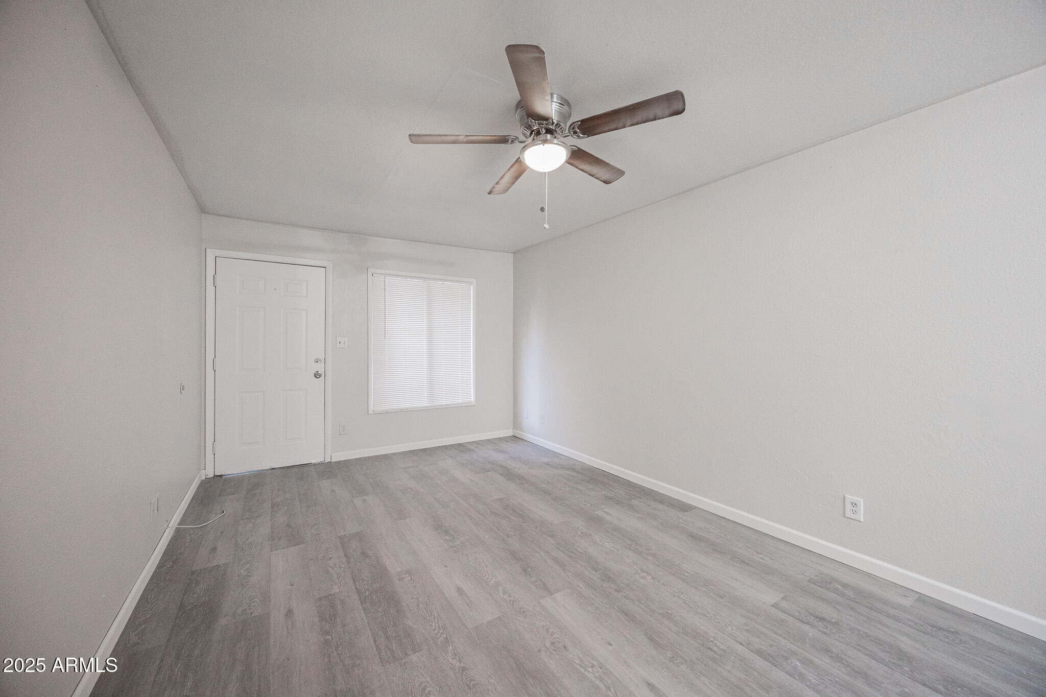2340 East Broadway Road, Unit A Mesa, AZ 85204 - Photo 5 of 14 a view of an empty room with wooden floor and a ceiling fan