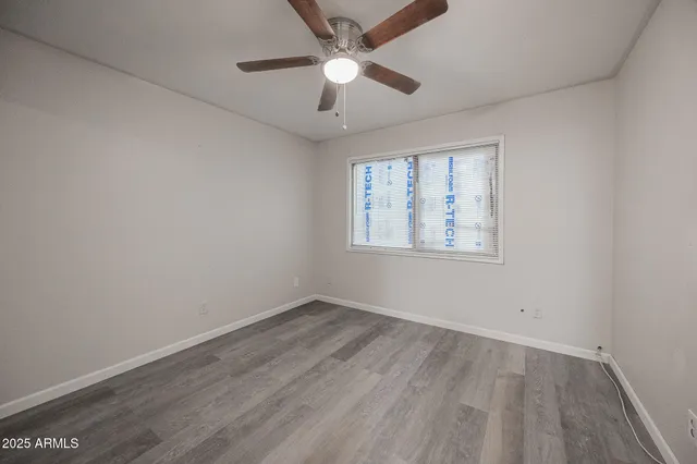 an empty room with wooden floor ceiling fan and windows