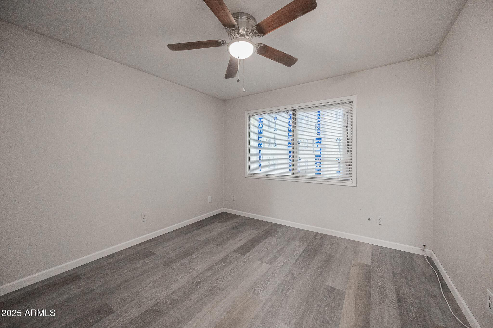 2340 East Broadway Road, Unit A Mesa, AZ 85204 - Photo 8 of 14 an empty room with wooden floor ceiling fan and windows