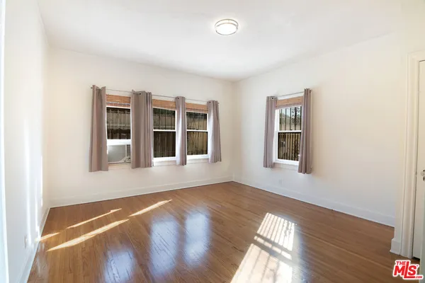 a view of an empty room with wooden floor and windows