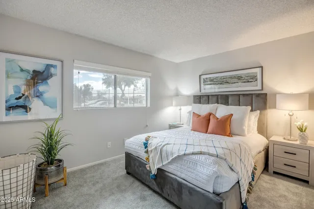 a bedroom with a large bed and potted plant on the dresser