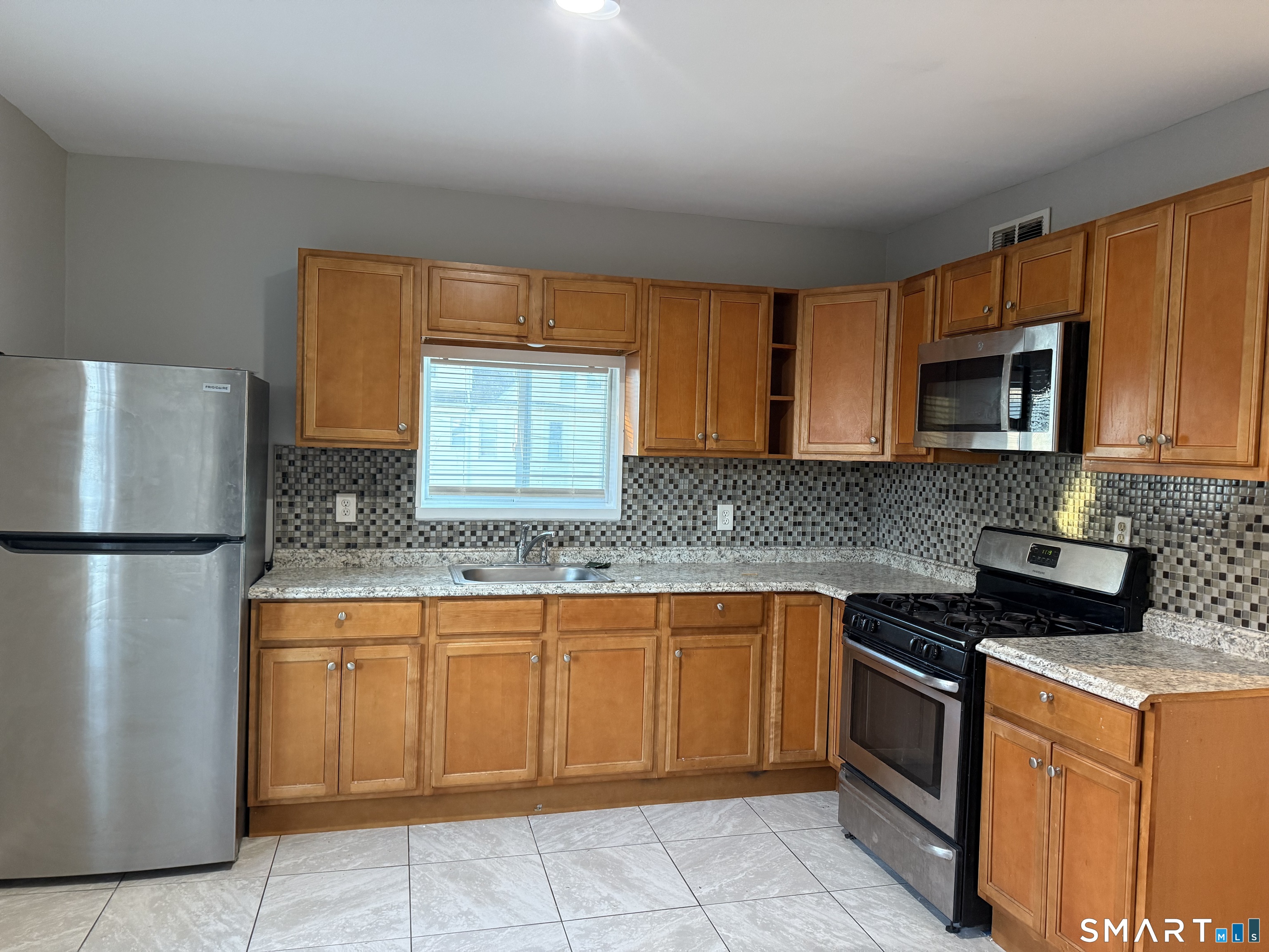 a kitchen with stainless steel appliances granite countertop a refrigerator sink and microwave