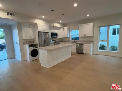 a kitchen with kitchen island a sink a stove a refrigerator cabinets and a counter top space