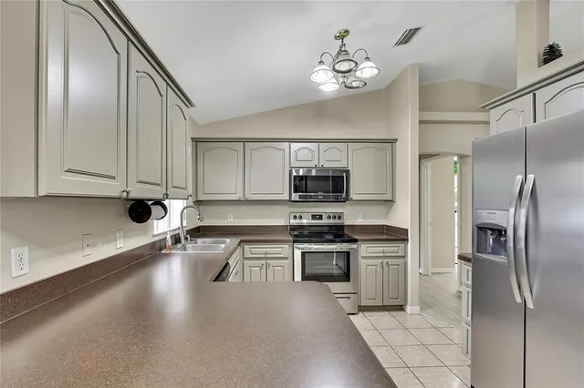 a kitchen with stainless steel appliances granite countertop a refrigerator a stove and a sink with wooden floor