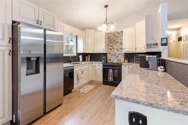 a kitchen with stainless steel appliances granite countertop a sink a stove and a refrigerator