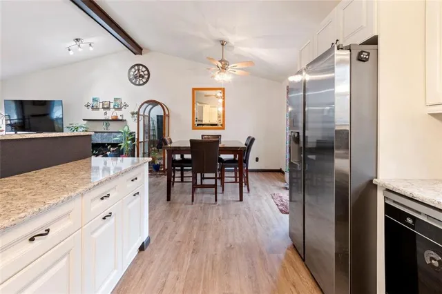 a kitchen with stainless steel appliances granite countertop a refrigerator a stove top oven a dining table and chairs with wooden floor