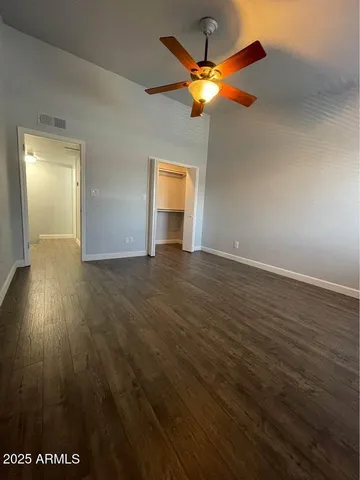 an empty room with wooden floor fan and window