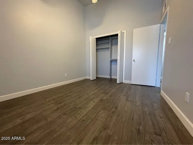 a view of an empty room with wooden floor and closet
