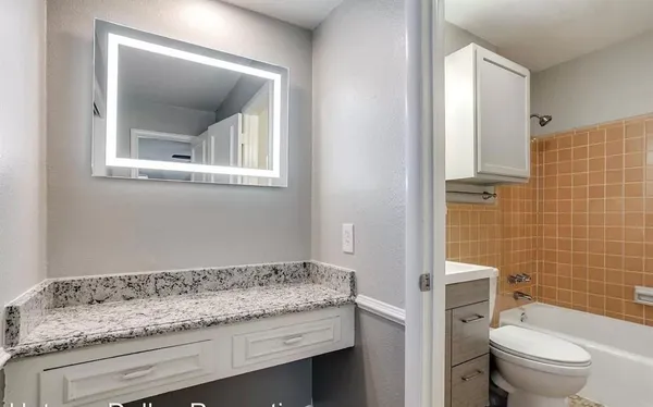 a bathroom with a granite countertop sink a toilet and mirror