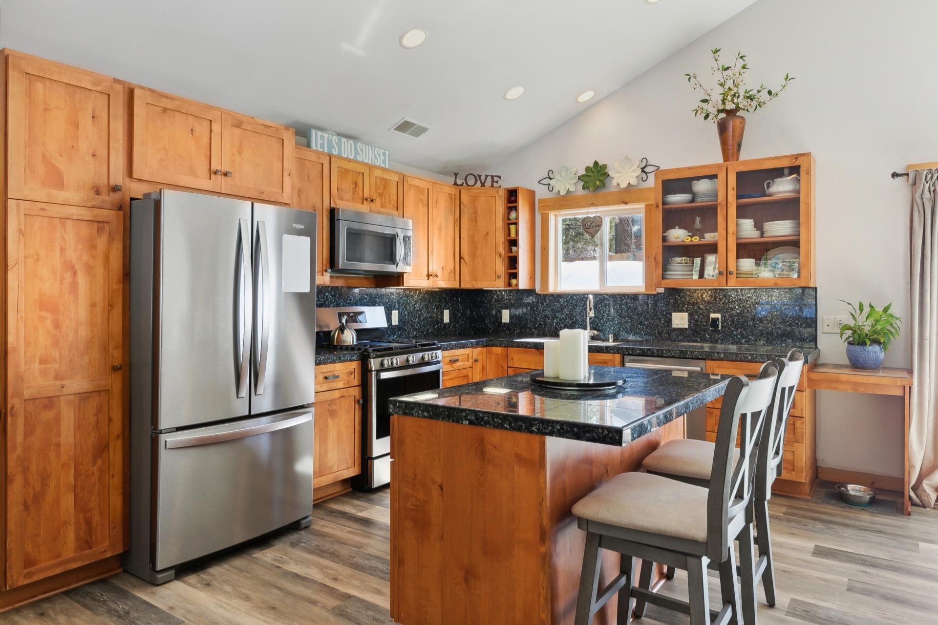 10383 Sugar Pine Road Truckee, CA 96161 - Photo 11 of 21 a kitchen with stainless steel appliances granite countertop a refrigerator a stove a sink a dining table and chairs with wooden floor