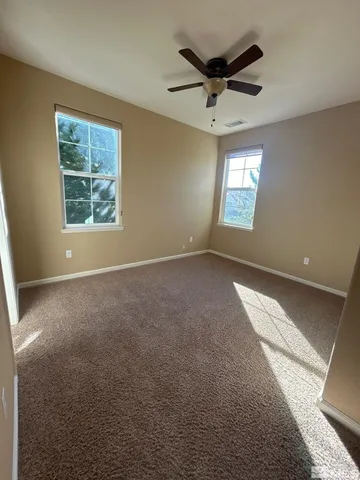 an empty room with windows and ceiling fan