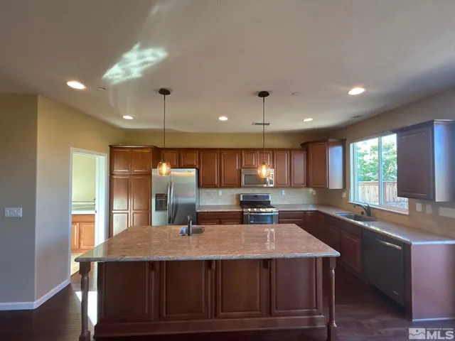 a kitchen with kitchen island a sink appliances and a large window