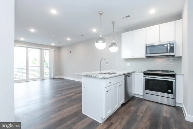 a large kitchen with stainless steel appliances granite countertop a stove a sink and a microwave