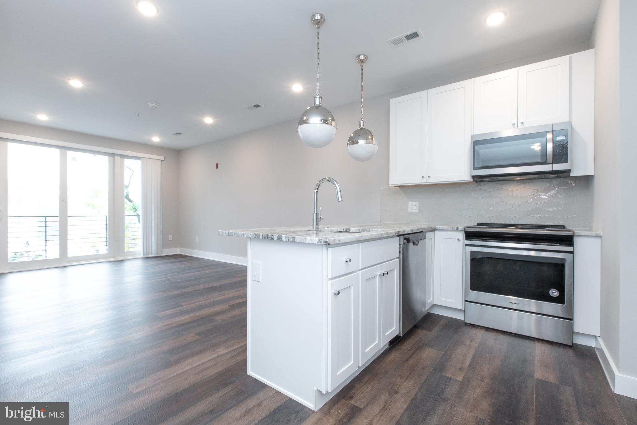 45 West Haines Street, Unit 303 Philadelphia, PA 19144 - Photo 2 of 24 a kitchen with stainless steel appliances granite countertop a stove a sink and a microwave
