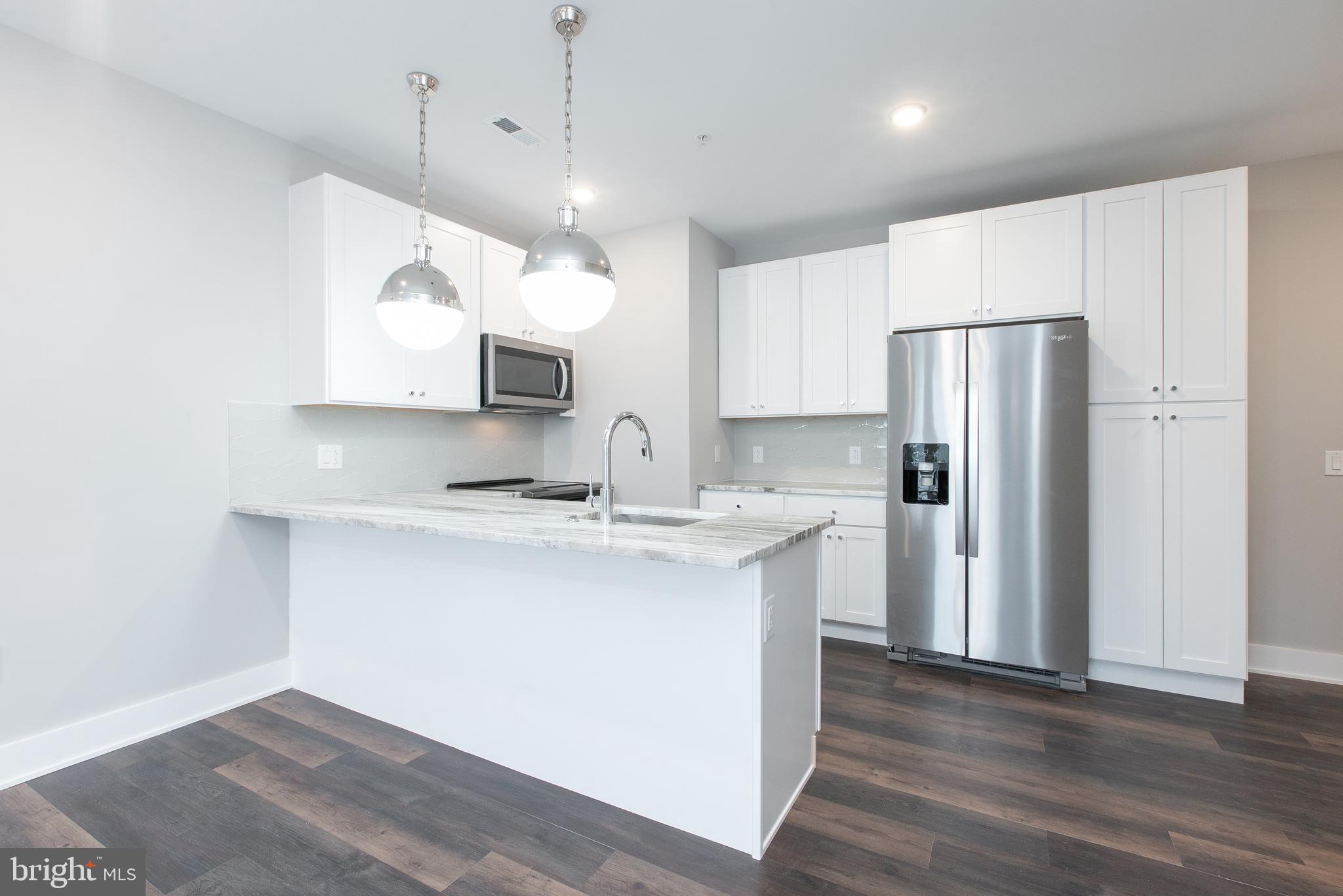 45 West Haines Street, Unit 303 Philadelphia, PA 19144 - Photo 7 of 24 a kitchen with kitchen island a sink stainless steel appliances and cabinets