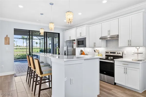 a kitchen with stainless steel appliances granite countertop a stove top oven a sink dishwasher and white cabinets with wooden floor