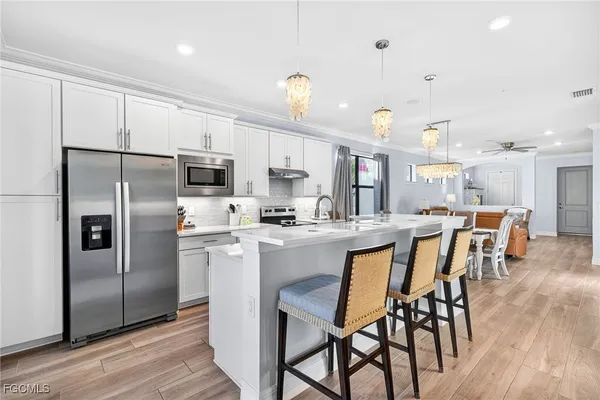 a kitchen with stainless steel appliances a dining table chairs stove and refrigerator