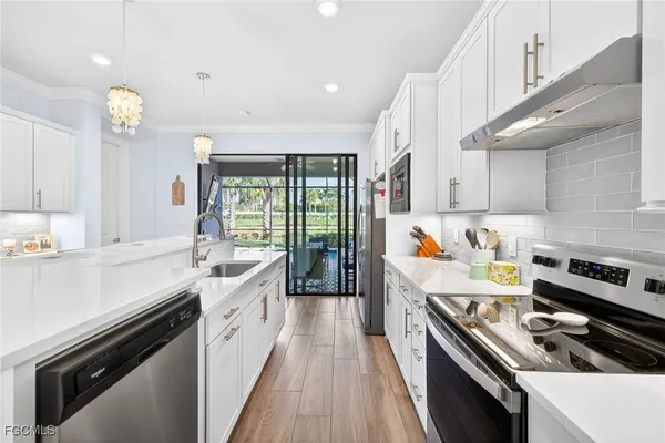 a kitchen with a stove a sink and wooden floor