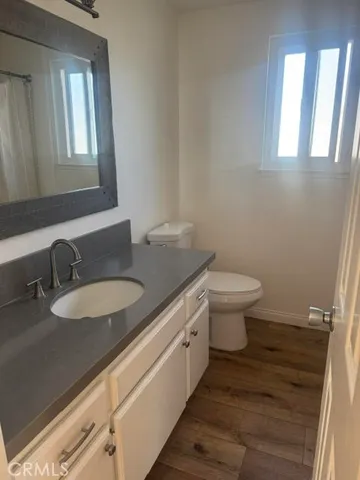 a bathroom with a granite countertop toilet a sink and a mirror