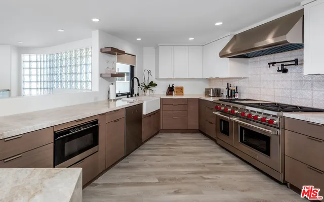 a kitchen with stainless steel appliances granite countertop a sink a stove and a wooden floors