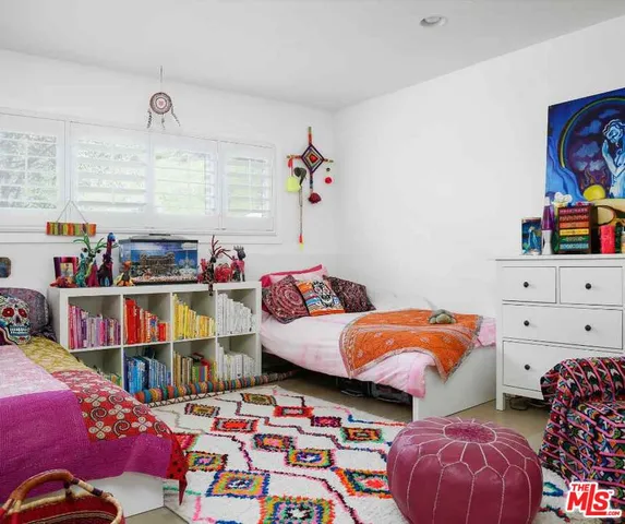 a bed room with two beds and a book shelf