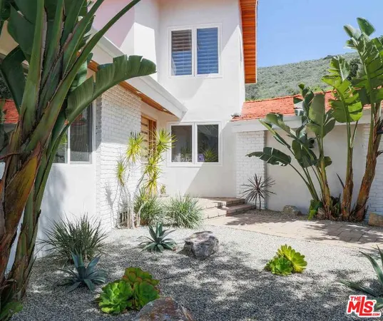 a patio with a table and chairs and potted plants
