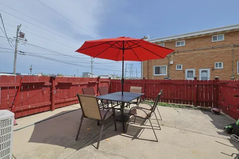 a view of a patio with a table and chairs under an umbrella