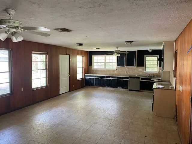 a large hall with stainless steel appliances granite countertop a large kitchen counter top a stove and a sink with dishwasher