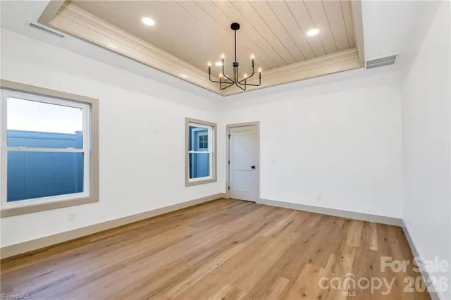 a view of an empty room with wooden floor and a chandelier