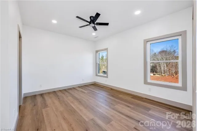 a view of empty room with wooden floor and window
